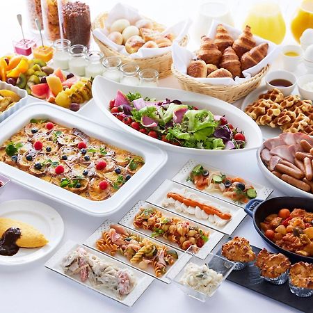 Yokohama Royal Park Hotel Экстерьер фото The photo displays a lavish breakfast spread featuring a variety of foods. There are fresh fruits, including slices of melon and berries, along with a selection of pastries such as croissants and muffins. A colorful salad is presented in a large dish